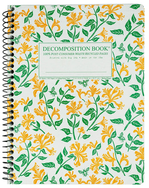 A spiral-bound decomposition book with a white cover decorated with a repeating pattern of yellow flowers and green leaves (honeysuckle). A white rectangular label on the front reads 'DECOMPOSITION BOOK' with smaller text below.