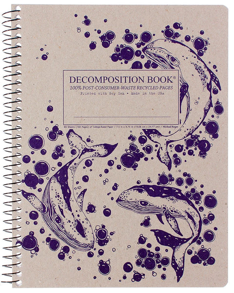 A spiral-bound decomposition book with a beige cover featuring three humpback whales and dark purple ink-blot illustrations. The cover text reads 'DECOMPOSITION BOOK' and '100% POST-CONSUMER-WASTE RECYCLED PAGES'. Printed with Soy Ink. Made in the USA. 