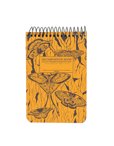 A spiral-bound decomposition notebook with a orange cover decorated with midnight moths and a tree illustration behind the moths. The center label reads 'DECOMPOSITION BOOK' 100% post -consumer-waste recycled pages. printed with soy ink, made in the usa