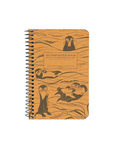 A spiral-bound pocket sized decomposition notebook with a tan cover printed with black illustrations of otters and kelp, plus a central label that reads 'DECOMPOSITION BOOK' and '100% POST-CONSUMER WASTE RECYCLED PAGES.'. Printed with Soy Ink. Made in the USA