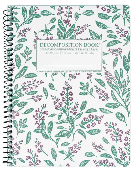 A spiral-bound decomposition book with a white cover decorated with a green and purple botanical pattern. A white label in the center reads 'DECOMPOSITION BOOK' with smaller text below.