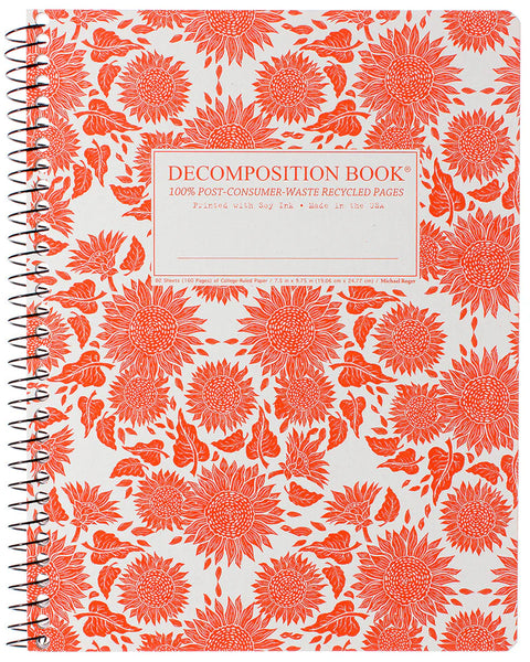 A spiral-bound decomposition book with a white cover covered in a bold orange floral and leaf patterns. The center features a white label with orange text that reads 'DECOMPOSITION BOOK' and '100% POST-CONSUMER-WASTE RECYCLED PAGES'. Printed with Soy Ink. Made in the USA