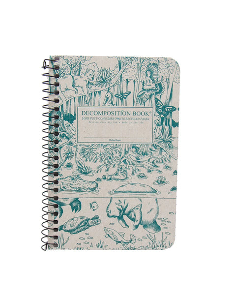 A spiral-bound pocket sized decomposition book with a beige cover printed in teal-green illustrations of everglades animals and plants, including a manatee, alligator, turtle, puma, and monarch butterflies. The front cover reads 'DECOMPOSITION BOOK' and '100% POST-CONSUMER WASTE RECYCLED PAGES. Printed with Soy Ink. Made in the USA.